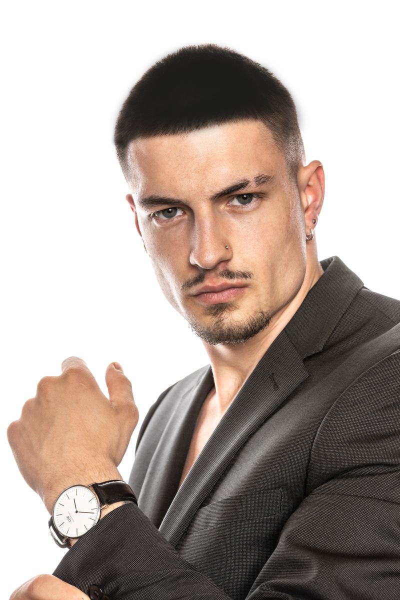 Nahaufnahme eines Mannes im Sakko mit Uhr vor weissem Hintergrund