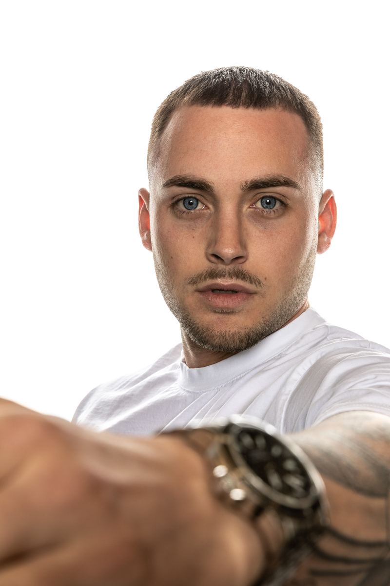 Mann im T-Shirt streckt die Hand mit Uhr zur Kamera