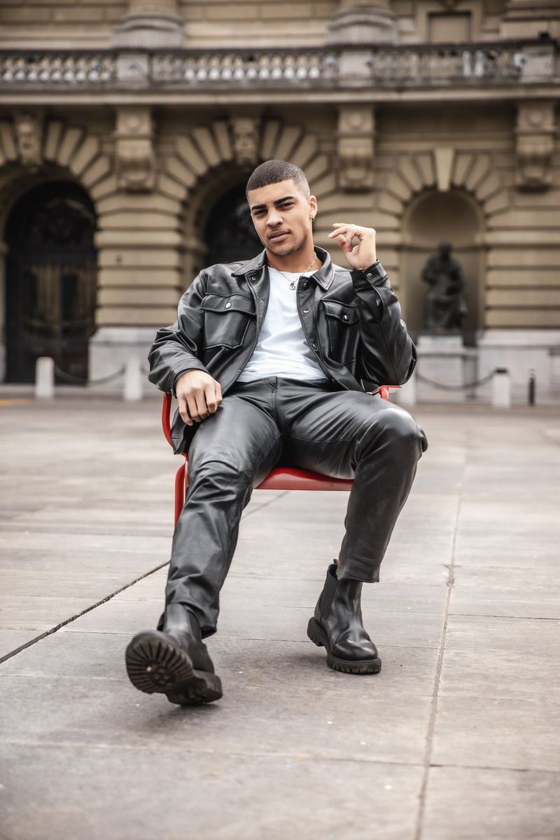 Mann in Lederjacke sitzt auf einem Stuhl vor dem Bundeshaus in Bern